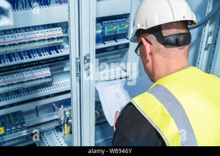 electrical engineer reads a wiring diagram in a control cabinet Stock Photo