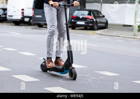 Close-up Of A Businessman Riding An Electric Scooter On City Road Stock Photo