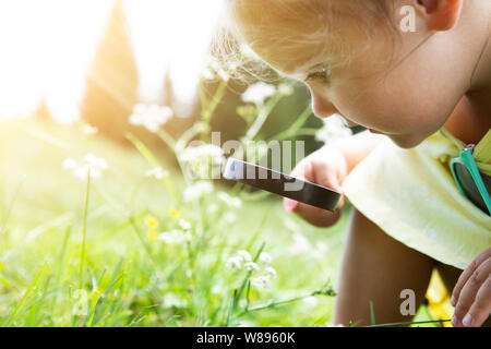 Little Girl Looking At Flower Through Magnifying Glass Stock Photo