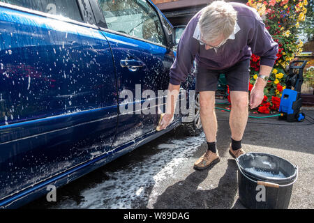 A man hand washes a car with a sponge and soapy water. Stock Photo