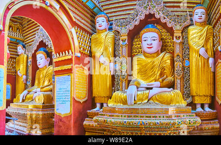 MONYWA, MYANMAR - FEBRUARY 22, 2018: The splendid interior of  Thanboddhay Paya decorated with large golden statues of Lord Buddha and colored carving Stock Photo