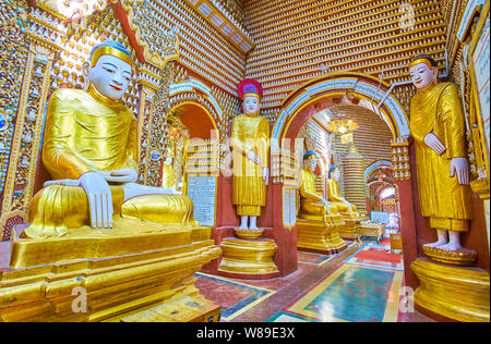 MONYWA, MYANMAR - FEBRUARY 22, 2018: The walk the reddish corridor of Thanboddhay Pagoda, lined with thousands of Buddha Images, standing, sitting and Stock Photo