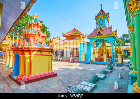 The beautiful shrines with bright walls, carved wooden pyatthat roofs and sculptures of mythical creatures in Thanboddhay monastery, Monywa, Myanmar Stock Photo