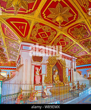 MONYWA, MYANMAR - FEBRUARY 22, 2018: Interior of Image House of Thanboddhay monastery with complex decorations of carved wood, stucco, gilt and tile, Stock Photo