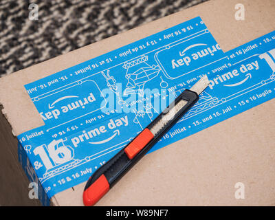 PARIS, FRANCE - JUL 4 2109: Cutter on top of new Amazon Prime Day cardboard parcel with special blue scotch tape for the Prime Day preparing to unbox Stock Photo