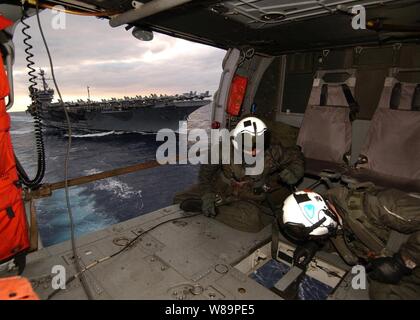 Navy aircrewmen Petty Officer 2nd class Joseph Broderick and Petty Officer 3rd class Christopher Lovell keep a watchful eye below as a cargo pallet is attached to the hook of their MH-60S Knighthawk helicopter during a vertical replenishment operation in the Atlantic Ocean on Dec. 6, 2004.  The Knighthawk is deployed aboard the USS Seattle (AOE 3) from Helicopter Combat Support Squadron 8.  The Seattle is a fast combat support ship that provides logistical support to the USS John F. Kennedy (CV 67) Carrier Strike Group.  Broderick is a Navy aviation machinist's mate and Lovell an aviation elec Stock Photo