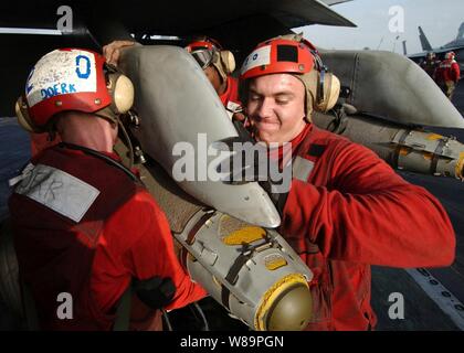 Marine Lance Cpl. Joshua Willis (right) and other Marines muscle a 500-pound JDAM bomb to the bomb rack of an F/A-18C Hornet on the flight deck of the aircraft carrier USS Harry S. Truman (CVN 75) on Feb. 9, 2005.  The Truman Strike Group and Carrier Air Wing 3 are conducting close air support, intelligence, surveillance, and reconnaissance missions over Iraq.  Willis and the Hornet are attached to Marine Fighter Attack Squadron 115 deployed from Marine Corps Air Station Beaufort, S.C. Stock Photo