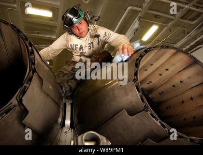 Petty Officer 2nd Class Christopher Shamblin wipes down the jet engine afterburner vanes on an F/A-18C Hornet in the hangar bay of the USS Harry S. Truman (CVN 75), on Feb. 22, 2005.  The Truman Strike Group and Carrier Air Wing 3 are conducting close air support, intelligence, surveillance, and reconnaissance missions over Iraq.  Shamblin is a Navy aviation structural mechanic assigned to Strike Fighter Squadron 37, of Naval Air Station Oceana, Va. Stock Photo