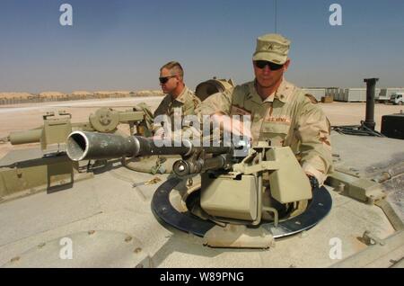 U.S. Army Sgt. Scott Junkin (right) mounts an M-240 machine gun on top of an M1A1 Abrams tank as he and Staff Sgt. Mark Gillentine make preparations for an upcoming mission at Forward Operating Base Hotel in Najaf Province, Iraq, on March 30, 2005.  Junkin and Gillentine are with Bravo Company, 1st Battalion, 198th Armor, 155th Brigade Combat Team, deployed from Tupelo, Miss., in support of Operation Iraqi Freedom. Stock Photo