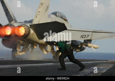 A waist catapult operator runs out after the launch of an F/A-18F Super Hornet to ready Catapult No. 3 for aircraft recovery on the flight deck of USS Kitty Hawk (CV 63) during the Joint Air and Sea Exercise on Aug. 8, 2005.  The USS Kitty Hawk Carrier Strike Group and the amphibious assault ship USS Boxer (LHD 4) are participating in the third annual Joint Air and Sea Exercise 2005 with the U.S. Air Force and Marine Corps in the western Pacific Ocean.  The exercise focuses on integrated joint training proficiency in detecting, locating, tracking, and engaging units at sea, in the air, and on Stock Photo