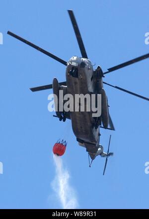 A U.S. Marine Corps CH-53E Super Stallion helicopter prepares to drop more than 2,000 gallons of water on a brushfire burning on Oahu, Hawaii, on Aug. 16, 2005. Eight military helicopters and nine Federal Fire Department fire engines came to the aid of the Honolulu Fire Department in extinguishing the blaze, which consumed more than 3,000 acres. Stock Photo