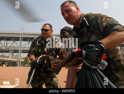 U.S. Air Force and Navy medical personnel lead a Hurricane Katrina victim to a Navy SH-60B Seahawk helicopter for airlift to an evacuation center in New Orleans, La., on Sept. 5, 2005.  Department of Defense units are mobilized as part of Joint Task Force Katrina to support the Federal Emergency Management Agency's disaster-relief efforts in the Gulf Coast areas devastated by Hurricane Katrina. Stock Photo