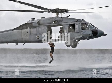 Navy Petty Officer 1st Class Eric Sutton jumps into the Pacific Ocean from a hovering MH-60S Seahawk helicopter during a search and rescue training exercise off the coast of Guam on Dec. 8, 2005.  Sutton, a Navy aviation machinist's mate, is a search and rescue swimmer attached to Helicopter Sea Combat Squadron 25 deployed to Anderson Air Force Base, Guam. Stock Photo