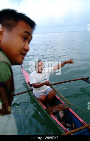 U.S. Navy Petty Officer 2nd Class Christopher Arntzen speaks with a local Filipino fishermen during a beach survey off the coast of Himbangan, Philippines, on Feb. 20, 2006.  Arntzen and his fellow sailors from the USS Harpers Ferry (LSD 49) are looking for places where landing craft can bring in search and rescue equipment and humanitarian relief supplies for the victims of the Feb. 17, 2006, Guinsaugon, Philippines mudslide disaster. Stock Photo