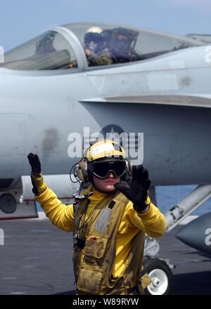 Navy Petty Officer 3rd Class Jeremy Sills looks for oncoming aircraft as he directs an F/A-18E Super Hornet aircraft to the catapult on the flight deck of the aircraft carrier USS Theodore Roosevelt (CVN 71) as the ship conducts flight operations in the Atlantic Ocean on April 23, 2006.  Sills is a Navy aviation boatswain's mate handler. Stock Photo