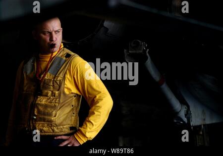 U.S. Navy Petty Officer 1st Class Joseph Jordan supervises the movement of aircraft in the hangar bay of the aircraft carrier USS Ronald Reagan (CVN 76) while under way in the Philippine Sea on June 22, 2006.  The Reagan Carrier Strike Group is participating in exercise Valiant Shield 2006, a joint exercise consisting of 28 naval vessels, more than 300 aircraft, and approximately 20,000 service members from the Navy, Army, Air Force, Marine Corps and Coast Guard. Stock Photo