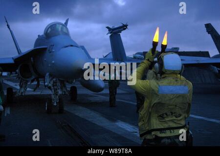 A Navy aircraft director signals the pilot of an F/A-18C Hornet to taxi to the catapult in preparation for launch from the flight deck of the USS Kitty Hawk (CV 63) as the ship operates in the Philippine Sea on June 22, 2006.  The Kitty Hawk Carrier Strike Group is participating in exercise Valiant Shield 2006, a joint exercise consisting of 28 naval vessels, more than 300 aircraft, and approximately 20,000 service members from the Navy, Army, Air Force, Marine Corps and Coast Guard. Stock Photo