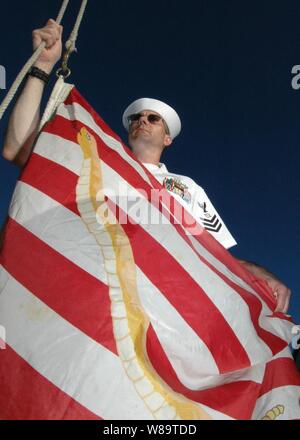 U.S. Navy Petty Officer 1st Class Stephen Cornell prepares to raise the Navy Jack onboard the USS Rueben James (FFG 57) during morning colors in Pearl Harbor, Hawaii, on Aug. 31, 2006.  The temporary substitution for the Union Jack represents an historic reminder of the nation's and Navy's origin and will to persevere and triumph during the war on terror. Stock Photo