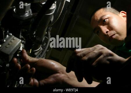 Petty Officer 2nd Class Christian Tan prepares a J52 jet engine for installation into an EA-6B Prowler aircraft in the hangar deck of the aircraft carrier USS Kitty Hawk (CV 63) as the ship operates in the waters off southern Japan on Nov. 3, 2006.  Tan is a U.S. Navy aviation machinist's mate onboard the carrier. Stock Photo