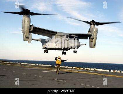 A flight deck crewman directs the crew of a U.S. Marine Corps CV-22 Osprey tilt rotor aircraft as they practice touch and go landings on the flight deck of the USS Wasp (LHD 1) as the ship operates in the Atlantic Ocean on Dec. 6, 2006.  The Osprey is from Marine Medium Tiltrotor Squadron 162 and is working on deck landing qualifications. Stock Photo