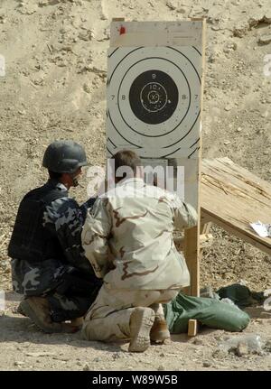 A U.S. Army soldier (right) from the 3rd Battalion, 10th Special Forces Group reviews a target while assisting an Iraqi Special Weapons and Tactics team member with properly sighting in his weapon during training at Camp Hit, Iraq, on Aug. 26, 2007. Stock Photo