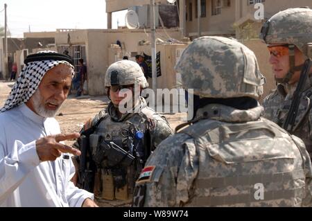 A village official explains village water supply problems to U.S. Army soldiers as they conduct a routine patrol in Isslah, Iraq, on Oct. 4, 2007.  The soldiers are from Bravo Battery, 2nd Battalion, 12th Field Artillery Regiment. Stock Photo