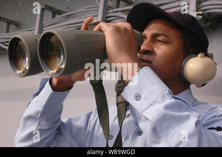 U.S. Navy Petty Officer 2nd Class Christopher Reid uses binoculars to look at commercial ships near the aircraft carrier USS Kitty Hawk's (CV 63) as the ship operates in the Pacific Ocean on March 3, 2008.  Reid is a Navy Intelligence Specialist onboard the carrier. Stock Photo