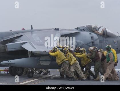 U.S. Navy crewmembers push an AV-8B Harrier aircraft onto an aircraft elevator aboard the Wasp class amphibious assault ship USS Essex (LHD 2) on April 29, 2008.  The Essex is the lead ship of a forward ñdeployed U.S. Expeditionary Strike Group. Stock Photo