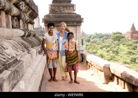 A Happy Female Tourist and Two Burmese Boys Smiling at  the Camera in the Thatbyinnyu Temple in Bagan Myanmar wearing Thanaka Makeup Woman Released. Stock Photo