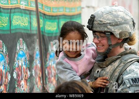 U.S. Army Spc. Melissa McIntyre of the 793rd Military Police Battalion, 8th Military Police Brigade holds a child while on patrol in the Hayyaniyah district of Basra, Iraq, on Jan. 20, 2009.  Her unit teamed with Iraqi police to deliver medical supplies to a local hospital. Stock Photo