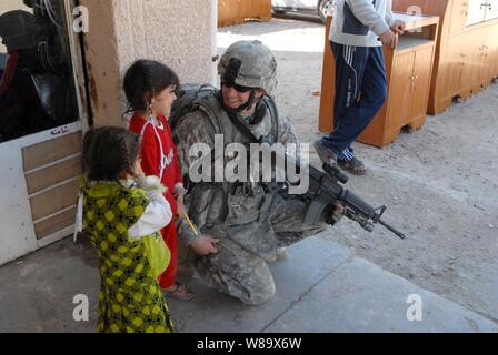 U.S. Army Pfc. Toby Barnes of 2nd Brigade Combat Team, 4th Infantry Division talks to two Iraqi girls during a joint patrol with Iraqi police to conduct post-election surveys in Iman, Iraq, on Feb. 3, 2009. Stock Photo