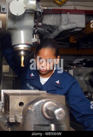 U.S. Navy Petty Officer 3rd Class Valerie Collier performs maintenance on a milling machine in the machinery shop aboard the amphibious assault ship USS Essex (LHD-2) in the East China Sea on June 17, 2009.