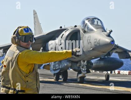 U.S. Navy Petty Officer 3rd Class Luccas Rosario prepares to launch an AV-8B Harrier aircraft from the flight deck of the amphibious assault ship USS Essex (LHD 2) in the Coral Sea on July 7, 2009. Stock Photo