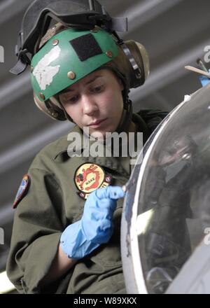 U.S. Marine Corps Cpl. Miranda Bouska, with Fixed Wing Marine Attack Squadron 211, and deployed to the amphibious assault ship USS Essex (LHD 2), applies sealant on the cockpit of a AV-8B Harrier aircraft in the ship's hanger bay while the ship is underway in the Coral Sea on July 11, 2009.  The Essex is the lead ship of the only forward-deployed expeditionary strike group and serves as the flagship for Combined Task Force 76, the Navy's only forward-deployed amphibious force command. Stock Photo