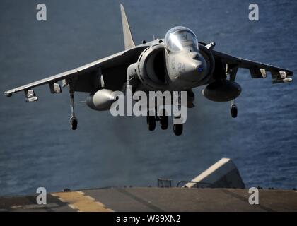 An AV-8B Harrier jet aircraft assigned to Marine Attack Squadron 211, embarked aboard the forward-deployed amphibious assault ship USS Essex (LHD 2), lands on the ship's flight deck while underway in the Coral Sea during a deck landing qualification evolution on July 7, 2009. Stock Photo