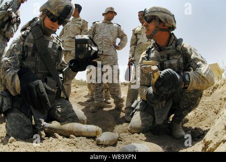 U.S. Army soldiers from the 787th Explosive Ordnance Disposal Company, 79th Explosive Ordnance Disposal Battalion, Task Force Troy assist Iraqi army soldiers from the 2nd Battalion, 24th Brigade, 6th Division catalog and dispose of live ordnance found during a weapons cache search outside Baghdad, Iraq, on Aug. 6, 2009. Stock Photo