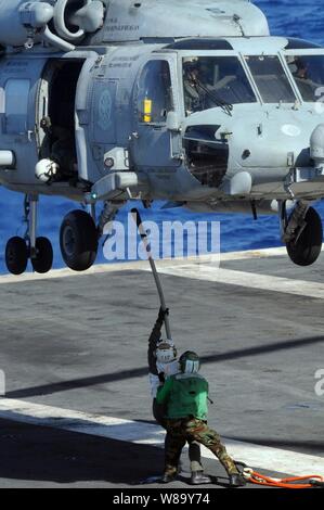 U.S. Navy sailors attach a cargo pendant to an HH-60H Seahawk helicopter assigned to Helicopter Anti-Submarine Squadron 4 during a vertical replenishment in the Pacific Ocean on July 16, 2010.  The USS Ronald Reagan (CVN 76) is participating in Rim of the Pacific, a biennial exercise that allows participating nations to build trust and enhance partnerships needed to improve maritime security. Stock Photo