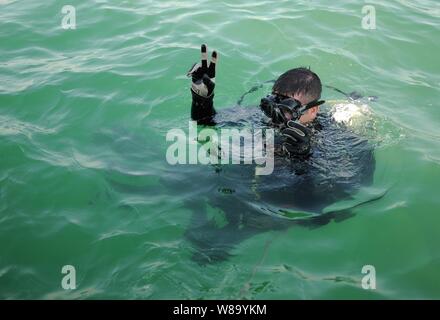 U.S. Navy Senior Chief Joseph Pendino, assigned to Mobile Diving and Salvage Unit 2, signals before diving under water while conducting an anti-terrorism force protection dive at Mina Salman Pier in Bahrain on Dec. 29, 2010.  Sailors with the salvage unit were deployed with Commander, Task Group 56.1, providing maritime security operations and theater security cooperation efforts in the U.S. 5th Fleet area of responsibility. Stock Photo