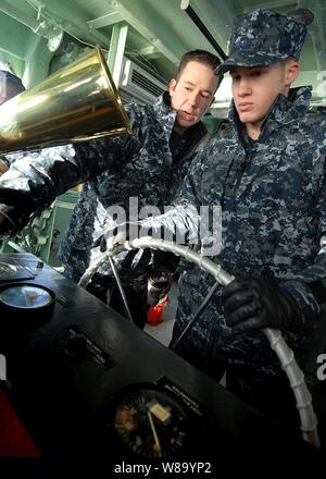 U.S. Navy Seaman Apprentice Jacob Horsch (right), assigned to Yard Patrol Operations at the U.S. Naval Academy, receives instruction from Petty Officer 2nd Class Christopher Abair while operating as the helmsman during a craft master qualification test in Annapolis, Md., on Jan. 13, 2011. Stock Photo