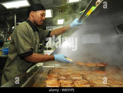 Seaman Diante A. Johnson prepares pork chops in the ship's galley for the crew aboard the guided-missile cruiser USS Anzio (CG 68) underway in the Pacific Ocean on Jan. 24, 2011. Stock Photo