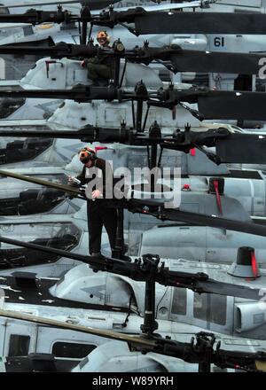 Marines conduct routine maintenance on helicopters assigned to Marine Medium Squadron 163 aboard the amphibious assault ship USS Boxer (LHD 4) underway in the Pacific Ocean on Feb. 24, 2011.  The Boxer and the 13th Marine Expeditionary Unit are deployed to the western Pacific region. Stock Photo