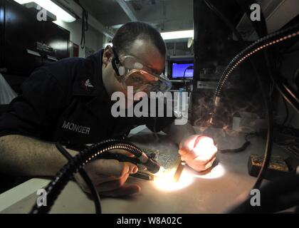 Petty Officer 2nd Class Christopher M. Monger repairs circuit cards aboard the aircraft carrier USS Enterprise (CVN 65) underway in the Arabian Sea on March 26, 2011.  The Enterprise and Carrier Air Wing 1 are conducting maritime security operations and close-air support missions for Operation Enduring Freedom in the U.S. 5th Fleet area of responsibility. Stock Photo