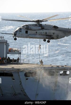 Marines from the Force Reconnaissance Platoon for the 24th Marine Expeditionary Unit fast rope out of an CH-53 Super Stallion assigned to Marine Medium Tilt Rotor Squadron 261 onto the Military Sealift Command fast combat support ship USNS Arctic (T-AOE 8) during a visit, board, search and seizure exercise aboard the amphibious transport dock ship USS New York (LPD 21) in the Atlantic Ocean on Dec. 4, 2011.  The New York is underway participating in a composite training unit exercise. Stock Photo