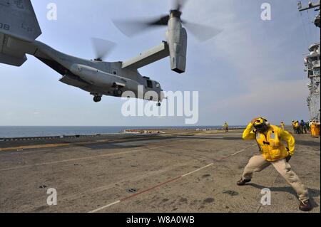 Chief Petty Officer Patrick Dewberry braces himself ¬against the rotor wash of a MV-22 Osprey launching from the deck of the amphibious assault ship USS Bonhomme Richard (LHD 6) in the Gulf of Thailand on Feb. 19, 2013.  The Bonhomme Richard Amphibious Ready Group is deployed in the U.S. 7th Fleet area of responsibility and is taking part in Cobra Gold 2013, a Thai-U.S. co-sponsored multinational joint exercise. Stock Photo