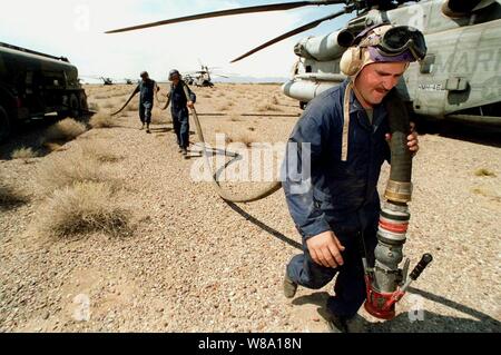 Marine Cpl. Paul Hardy hauls a fuel hose from a M970 fuel truck to a waiting helicopter at the Forward Area Refueling Point near Yuma, Ariz., on April 17, 1997, during Exercise Desert Punch.  Desert Punch is a simulated helicopter assault mission involving over 60 helicopters from nine squadrons of Marine Aircraft Group 16.  The helicopters launched from Marine Corps Air Stations El Toro and Tustin, Calif., and rendezvoused at the designated landing zone outside Yuma.  Marines from Marine Wing Support Squadron 371, Marine Corps Air Station Yuma, set up and supported the refueling point. Stock Photo