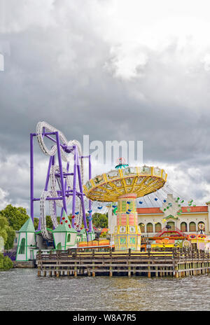 Flying swings merry go round ride, roller coaster at Tivoli Grona Lund amusement park Stockholm Sweden via Lake Malaren grey storm clouds threaten
