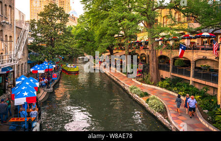 San Antonio River walk in daytime with tourists sitting on patios and on path. Stock Photo