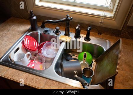 Stack of dirty dishes piled into the kitchen sink Stock Photo