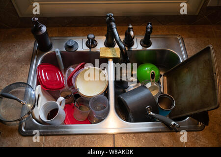 Stack of dirty dishes piled into the kitchen sink Stock Photo