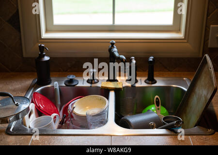 Stack of dirty dishes piled into the kitchen sink Stock Photo